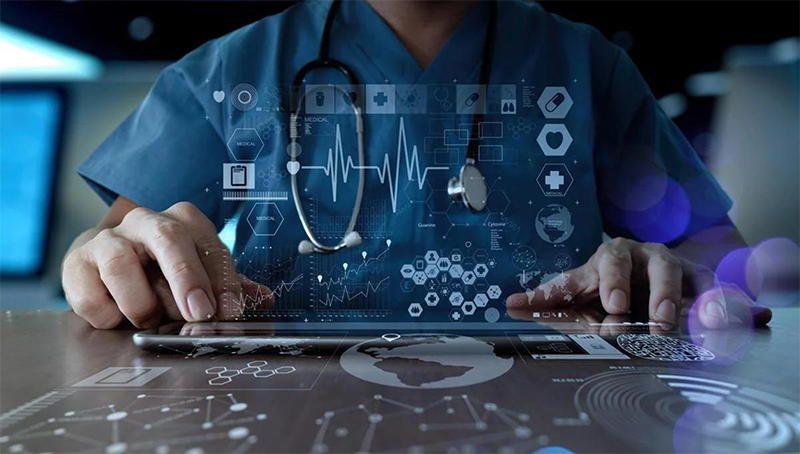 clinician wearing scrubs and stethoscope working on a tablet with high-tech 3D icons related to healthcare