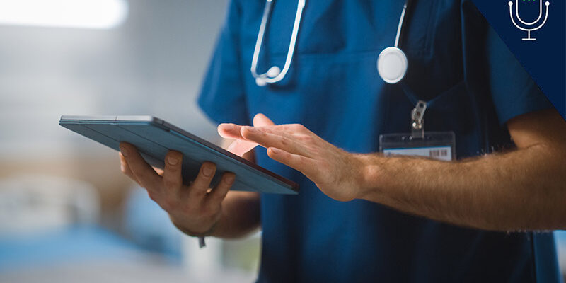 Close up of nurse, from shoulder to waist, using iPad while wearing scrubs and stethoscope