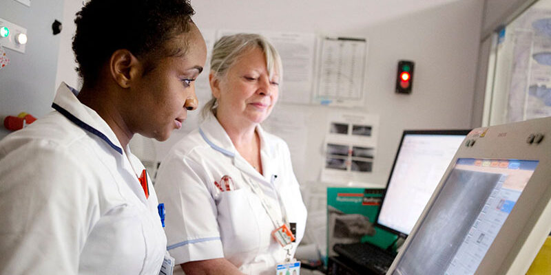 Two nurses working on a computer screen and x-ray monitor