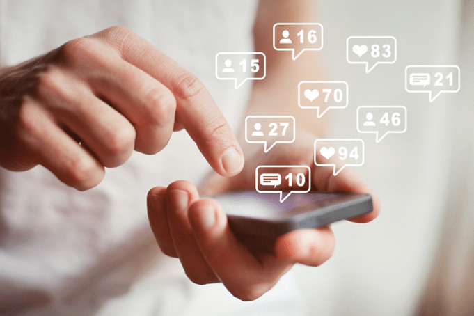 close up of hands holding smartphone with various engagement icons