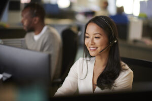 Woman working at call center wearing headset and on computer