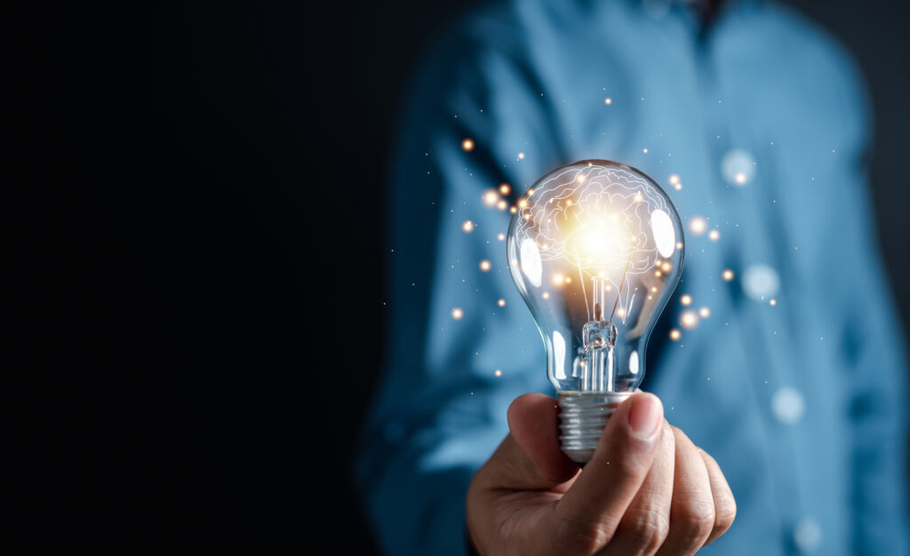 Person wearing blue shirt holding a light bulb with an illustration of a brain on the inside