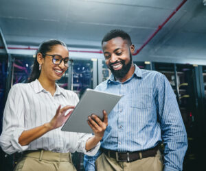 Shot of two young technicians using a digital tablet while working in a server room Two IT technicians using a digital tablet while working in a server room